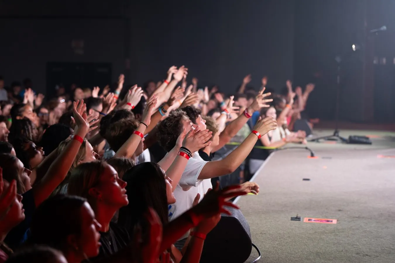 Students worshiping at camp with hands raised toward the stage